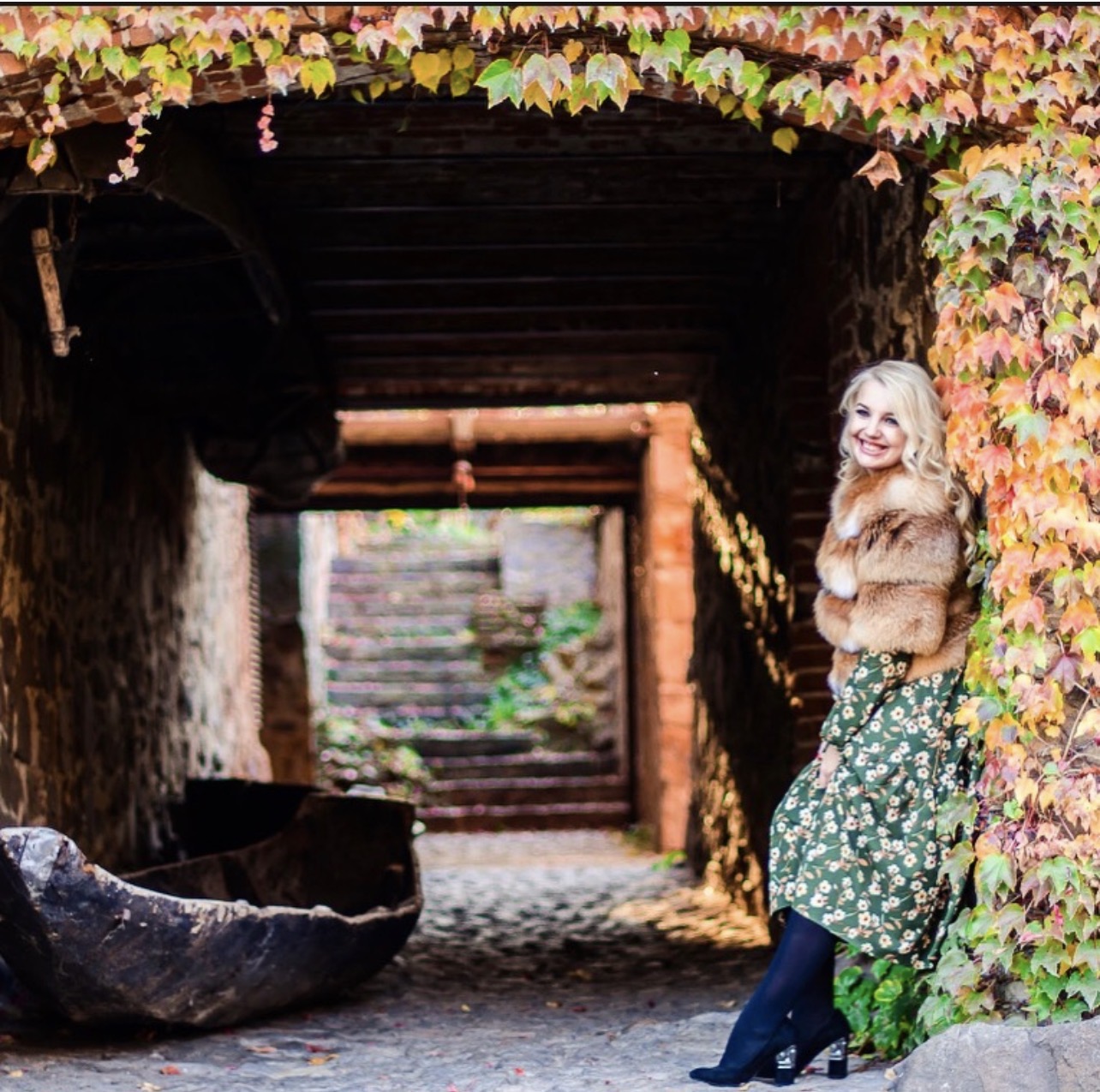 Ukrainian artist Marina Stognieva beside a vine-covered arch at Radomysl Castle